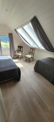 Kyrkjebø Apartment的一间卧室设有两张床、两把椅子和窗户。
