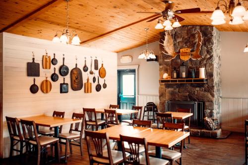 麦金利公园迪纳利小屋旅馆的餐厅设有木桌、椅子和壁炉