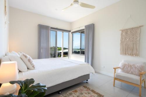 凯阿玛Sea&Country Kiama - Stunning Views-Relaxing-Spacious-Deck-EVC的白色的卧室设有床和窗户