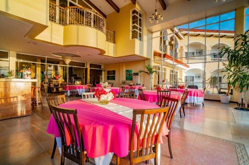 公主港Hotel Palacio Puerto Princesa的用餐室配有粉红色的桌椅