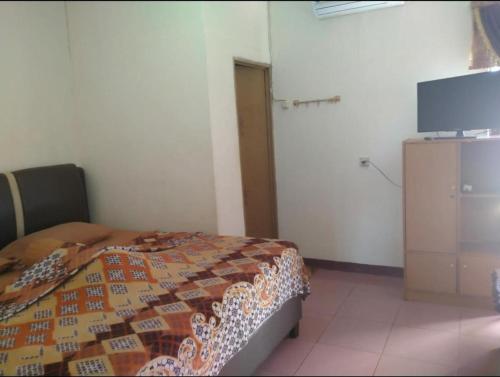 LampungCut Nyak Dien Guest House的一间卧室配有一张床和一台平面电视