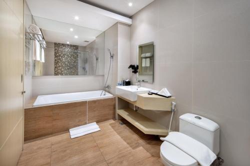 沙努尔Four Star by Trans Hotel的带浴缸、卫生间和盥洗盆的浴室