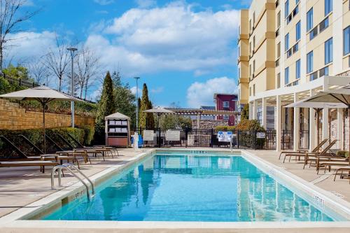 利西亚斯普林斯Fairfield Inn & Suites by Marriott Atlanta Lithia Springs的一座带椅子和遮阳伞的游泳池位于一座建筑旁边
