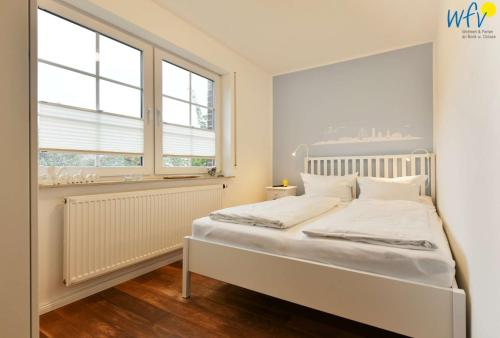 于斯德Luv und Lee - Ferienwohnung Juister Stuv的窗户客房内的一张白色床