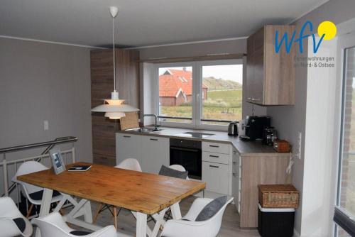 于斯德Haus Kiek in't Watt Ferienwohnung Deichrausch的厨房配有木桌和白色椅子