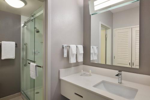 迈尔斯堡珊瑚角迈尔斯堡万怡酒店 的一间带水槽、镜子和淋浴的浴室