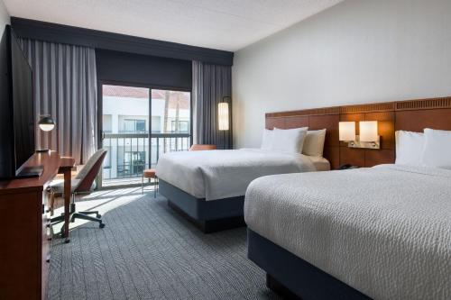 凤凰城Courtyard by Marriott Phoenix North的酒店客房设有两张床、一张书桌和一个窗户。