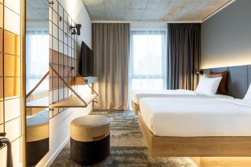 梅青根Moxy Outletcity Metzingen的酒店客房设有两张床和窗户。