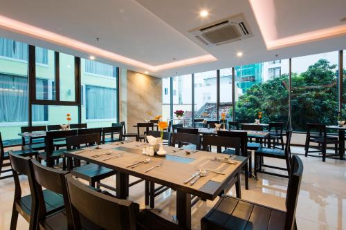 芽庄Daisy Flower Nha Trang的餐厅设有木桌和椅子以及大窗户。