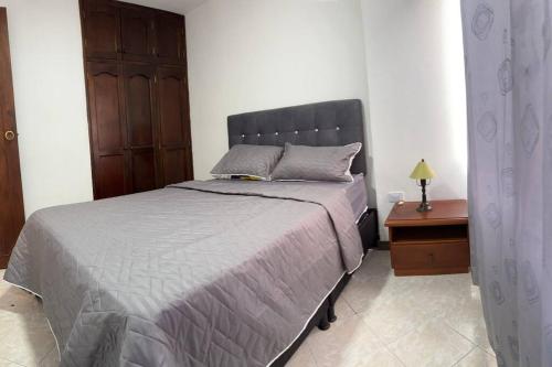 贝约Apartamento en Bello Medellín的一间卧室配有一张床和一张桌子及床头柜