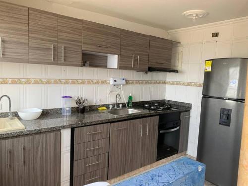 卡塔赫纳Apartamento en Cartagena cerca del aeropuerto的厨房配有木制橱柜和不锈钢冰箱。