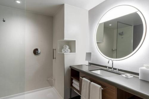 夏洛特Courtyard by Marriott Charlotte Waverly的一间带水槽、镜子和淋浴的浴室