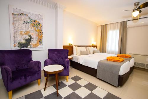 博德鲁姆Hotel Pier Bodrum Marina的酒店客房,配有一张床和两张紫色椅子