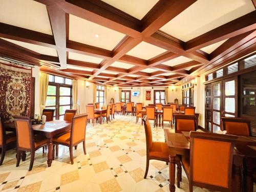 琅勃拉邦Houngvilai Hotel的餐厅设有木桌、椅子和窗户。