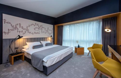 瓦拉日丁帕克精品酒店的一间卧室配有一张大床和一张黄色椅子