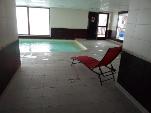 贝斯和圣阿纳斯泰斯Appartement dans residence de tourisme的一座带红色椅子的游泳池