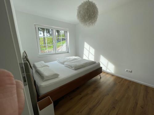 施瓦格明德Gemütliche Wohnung im Herzen von Schwäbisch Gmünd的一间卧室配有一张带白色床单的床和一扇窗户。