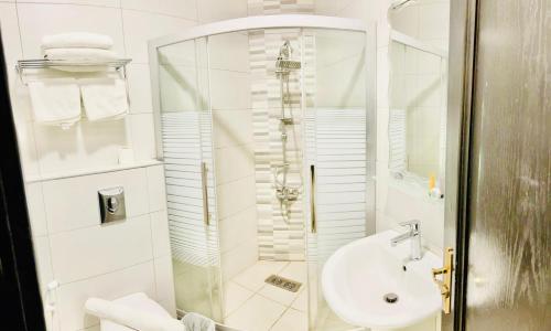 安曼Panorama Amman Hotel的带淋浴和盥洗盆的白色浴室