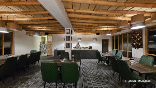洪达尔Eden Resort Nubra的餐厅设有桌子、绿色椅子和柜台
