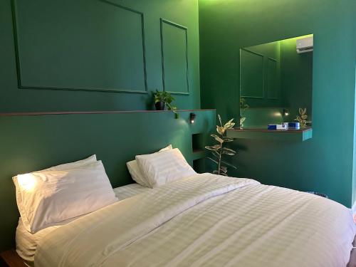 Al Mutaynīyātشاليهــات داكــن的卧室配有白色的床和绿色的墙壁