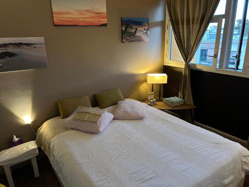 巴黎A L'OMBRE DE LA TOUR EIFFEL AU BORD DE LA SEINE的卧室配有带枕头的床铺和窗户。