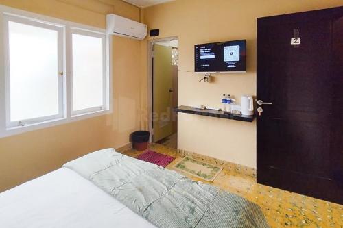 班达楠榜Arwana Inn Lampung RedPartner的一间卧室设有一张床、一扇门和一台电视