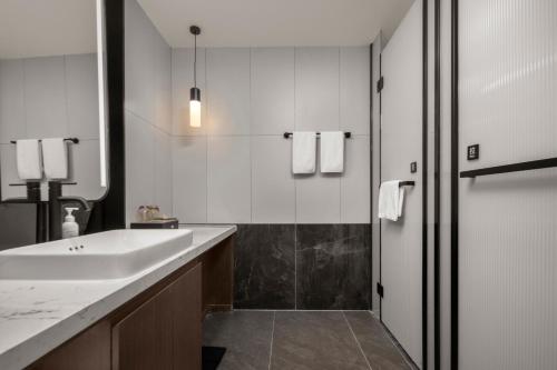 黄山市美豪酒店黄山高铁北站店的白色的浴室设有水槽和淋浴。