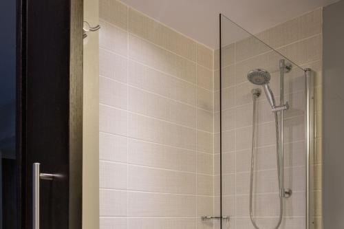 皇后区纽约肯尼迪机场万怡酒店的浴室里设有玻璃门淋浴