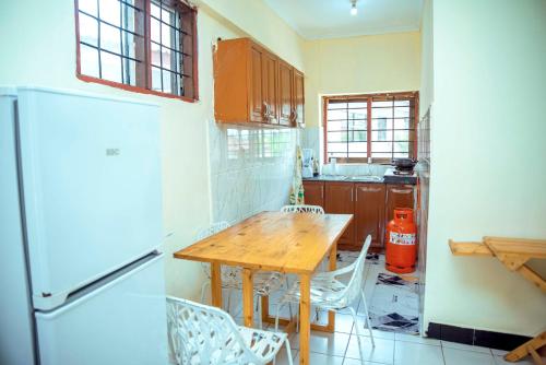 达累斯萨拉姆Travellers Home near Mlimani City Mall with free parking的厨房配有木桌和冰箱。