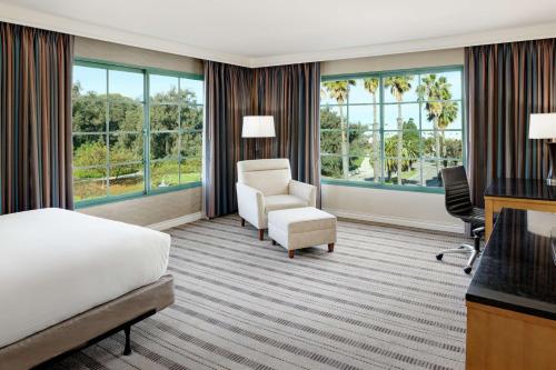 圣佩德罗圣佩德罗希尔顿逸林酒店的酒店客房带一张床、椅子和窗户