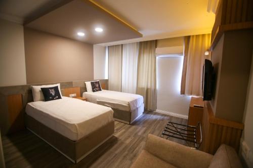 安塔利亚ÇEVİK PALACE HOTEL的酒店客房设有两张床和电视。
