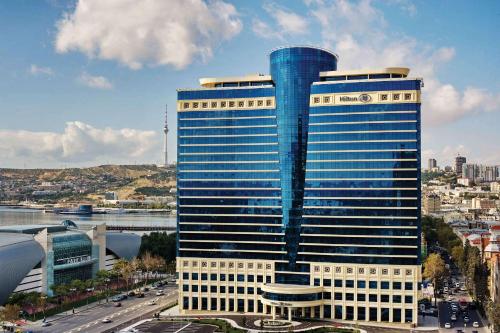 巴库巴库希尔顿酒店的一座高大的建筑,有蓝色的窗户,位于城市