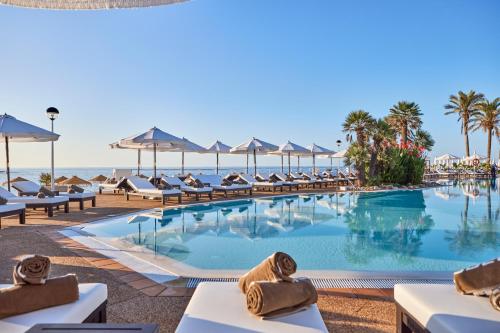 萨尔加AluaSoul Menorca - Adults Only的海滩上的游泳池配有椅子和遮阳伞