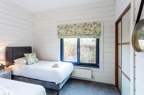 罗伊登Roydon Marina - Lodge 1 - Hot Tub的一间卧室设有两张床和窗户。