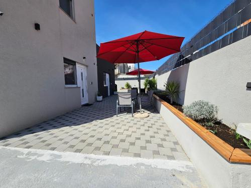 扎达尔Apartments Anamarija的一个带椅子和红色遮阳伞的庭院
