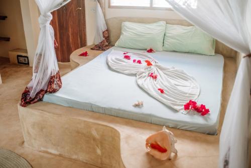 江比阿Marvelous Zanzibar的一张铺有白色床单和红色鲜花的床
