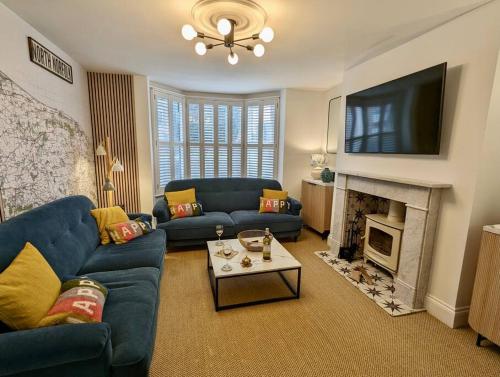 谢林汉姆Happy Place, Sheringham Stunner - Crabpot Cottages Sheringham的客厅设有蓝色的沙发和壁炉
