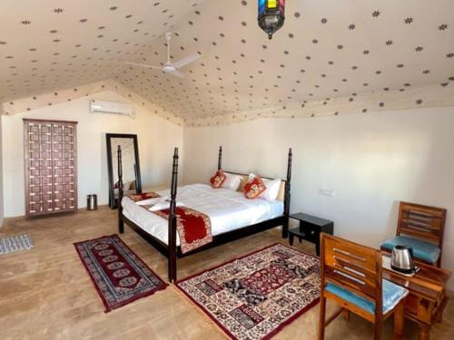 斋沙默尔Royal Luxury Camp Jaisalmer的一间卧室配有一张床、一张桌子和一张四柱床。