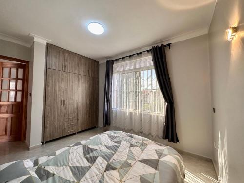 坎帕拉Amy Luxury Apartments In Munyonyo的一间卧室设有一张床和一个大窗户