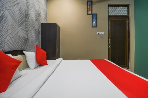 SūbedārganjOYO Jk Mahal的一间卧室配有一张带红色枕头的大床