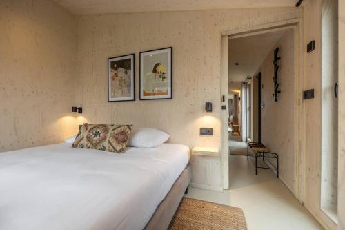 韦斯特卡佩勒Hello Zeeland - Tiny House Zeeuwse Liefde 12的卧室设有一张白色大床和一个走廊