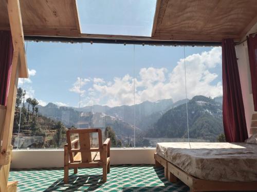 马恩迪Stargazing Glass Lodge Himachal Pradesh Thachi的卧室设有大窗户、一张床和一把椅子