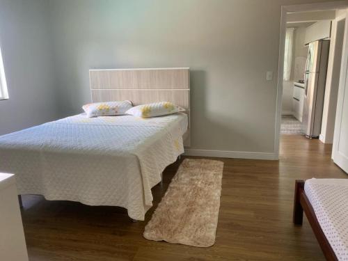 布卢梅瑙Blumen Espaço "piscina privativa'的一间卧室配有一张带白色毯子和地毯的床。