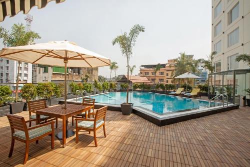 古瓦哈提ARISTA BY AMBITION的一个带桌椅的庭院和一个游泳池