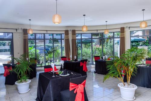 基加利One Click Hotel的一间设有红色弓形和植物的黑桌的餐厅