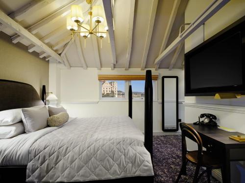 巴斯Abbey Hotel Bath, a Tribute Portfolio Hotel的一间卧室配有一张床、一张书桌和一台电视。