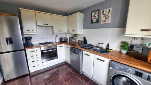 普里茅斯New - Modern Home from Home, 3 bedrooms, 2.5 bath的厨房配有白色橱柜、洗衣机和烘干机