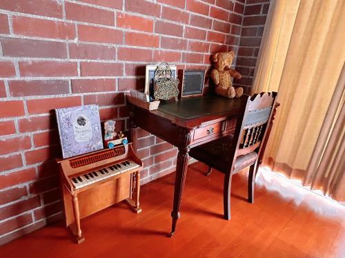 恩纳猫とピアノと星空のリゾートブティックコテージ - Starry Forest Cottage Okinawa -的砖墙旁一张桌子,上面有塞满的熊和椅子