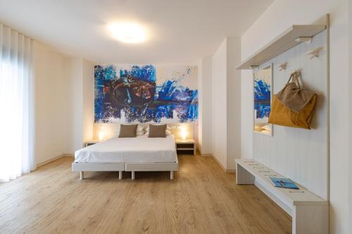 利尼亚诺萨比亚多罗Art Hotel Principe的卧室配有一张床,墙上挂有绘画作品