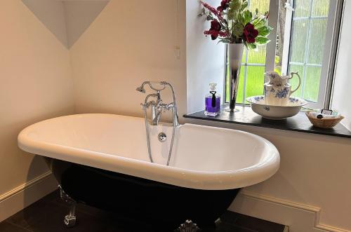 林顿Exmoor Manor Guest House的带浴缸的浴室,花瓶